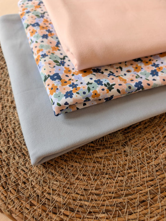 Cotton jersey Brooke Floral fabric stacked with plain cotton jersey in peach and powder blue — pastel multi ditsy floral print on white