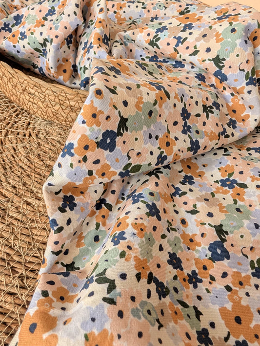 Cotton jersey fabric folded on a rattan placemat — Brooke Floral pastel multi ditsy floral print on white cotton jersey