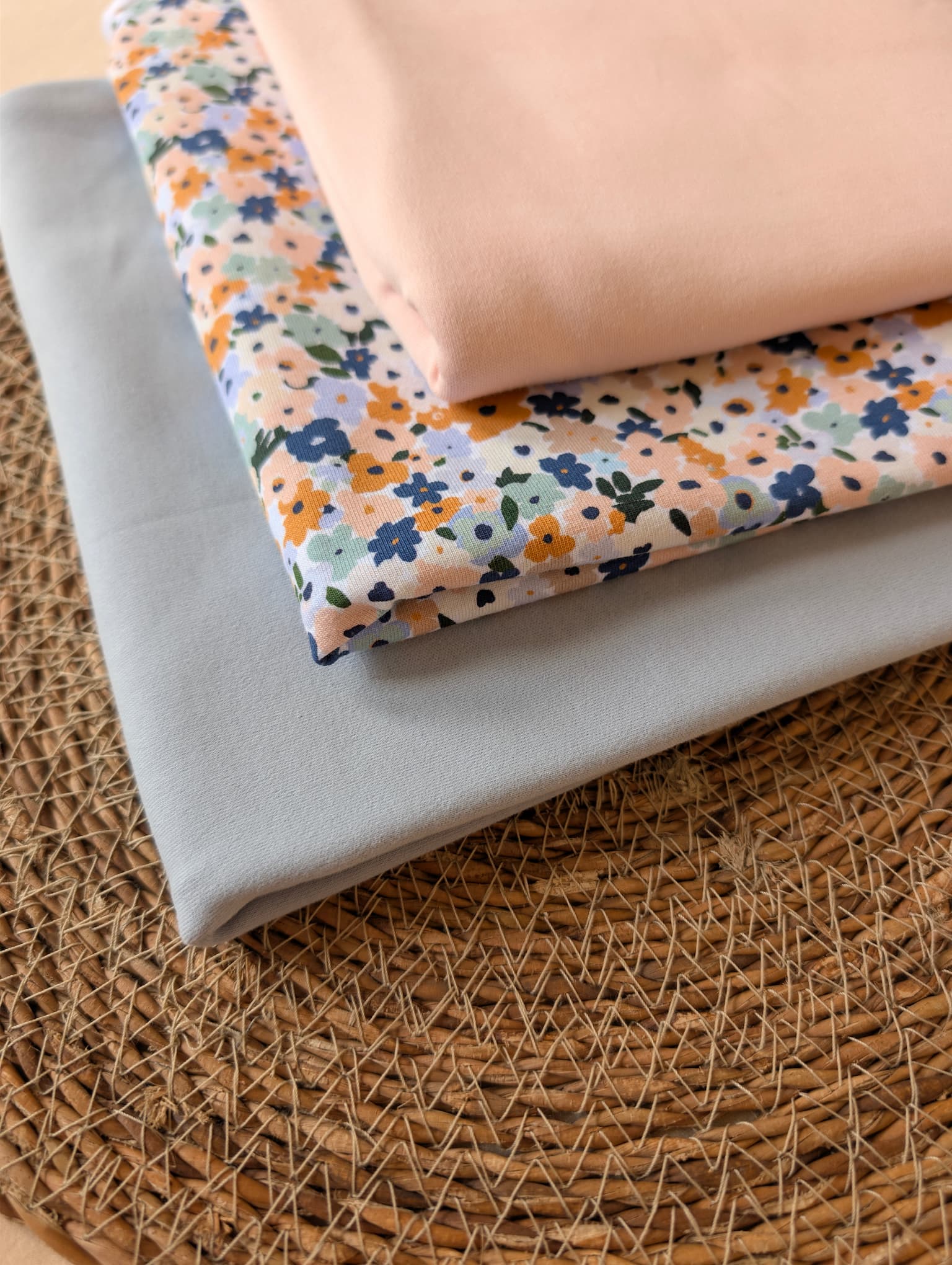 Cotton jersey Brooke Floral fabric stacked with plain cotton jersey in peach and powder blue — pastel multi ditsy floral print on white