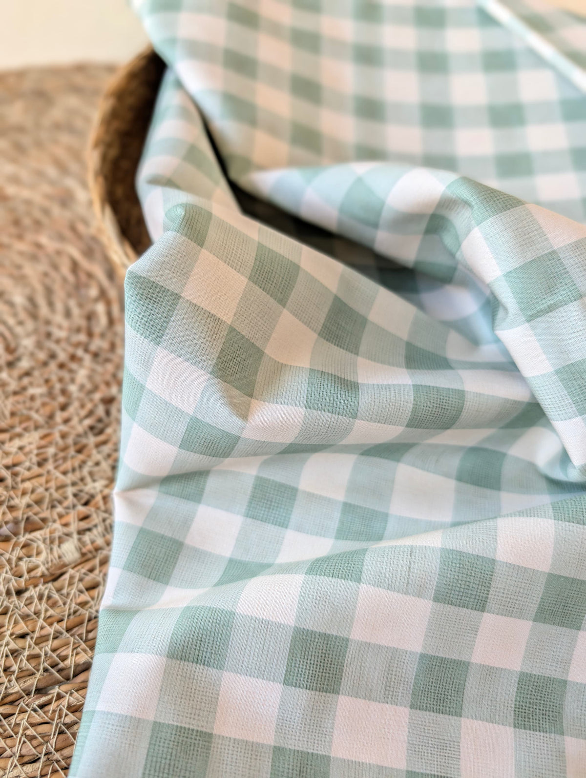 Celeste Sage Gingham Check Cotton — sage green and white gingham fabric draped over a wicker basket