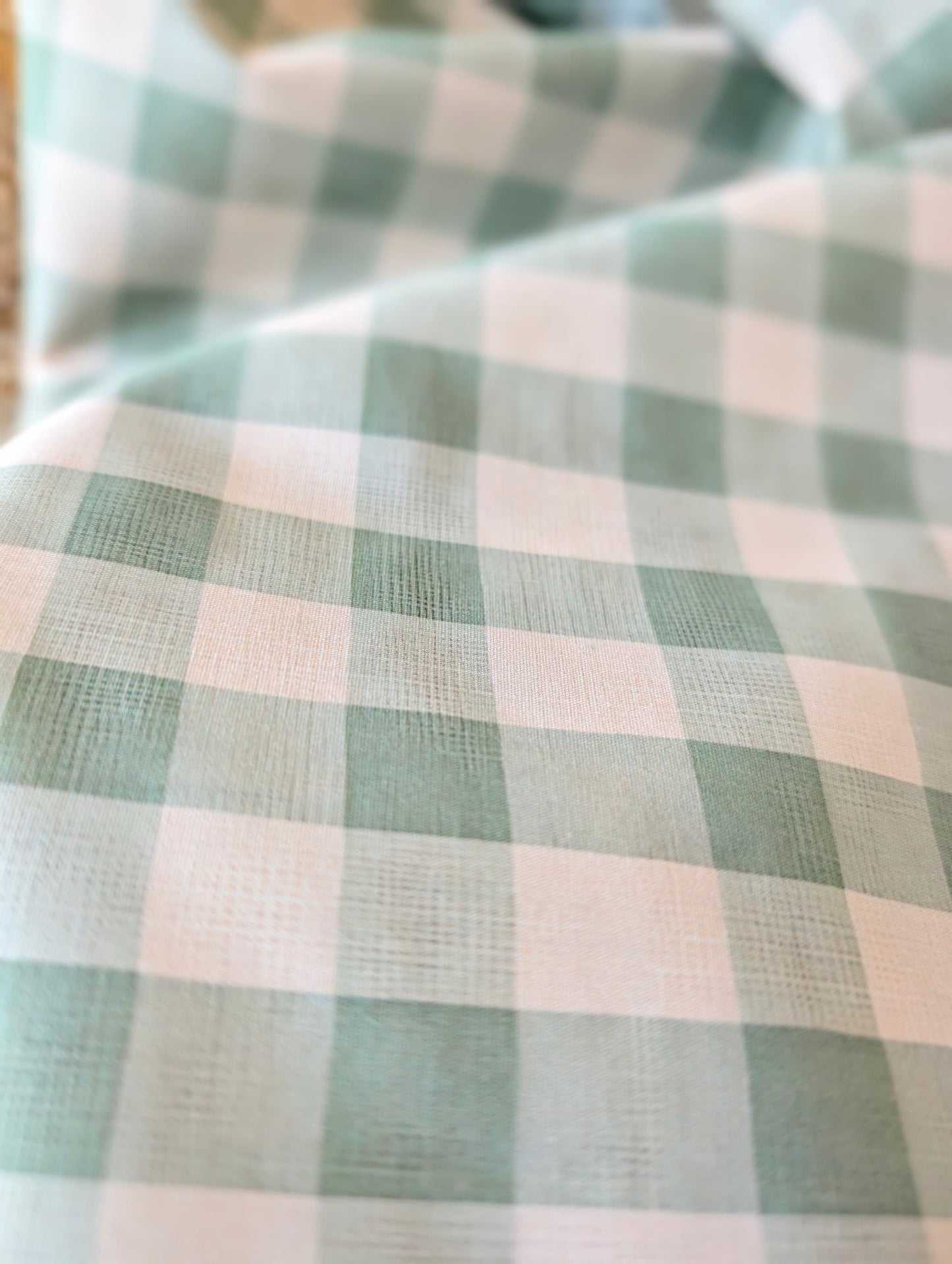 Celeste Sage Gingham Check Cotton — sage green and white gingham fabric draped over a wicker basket