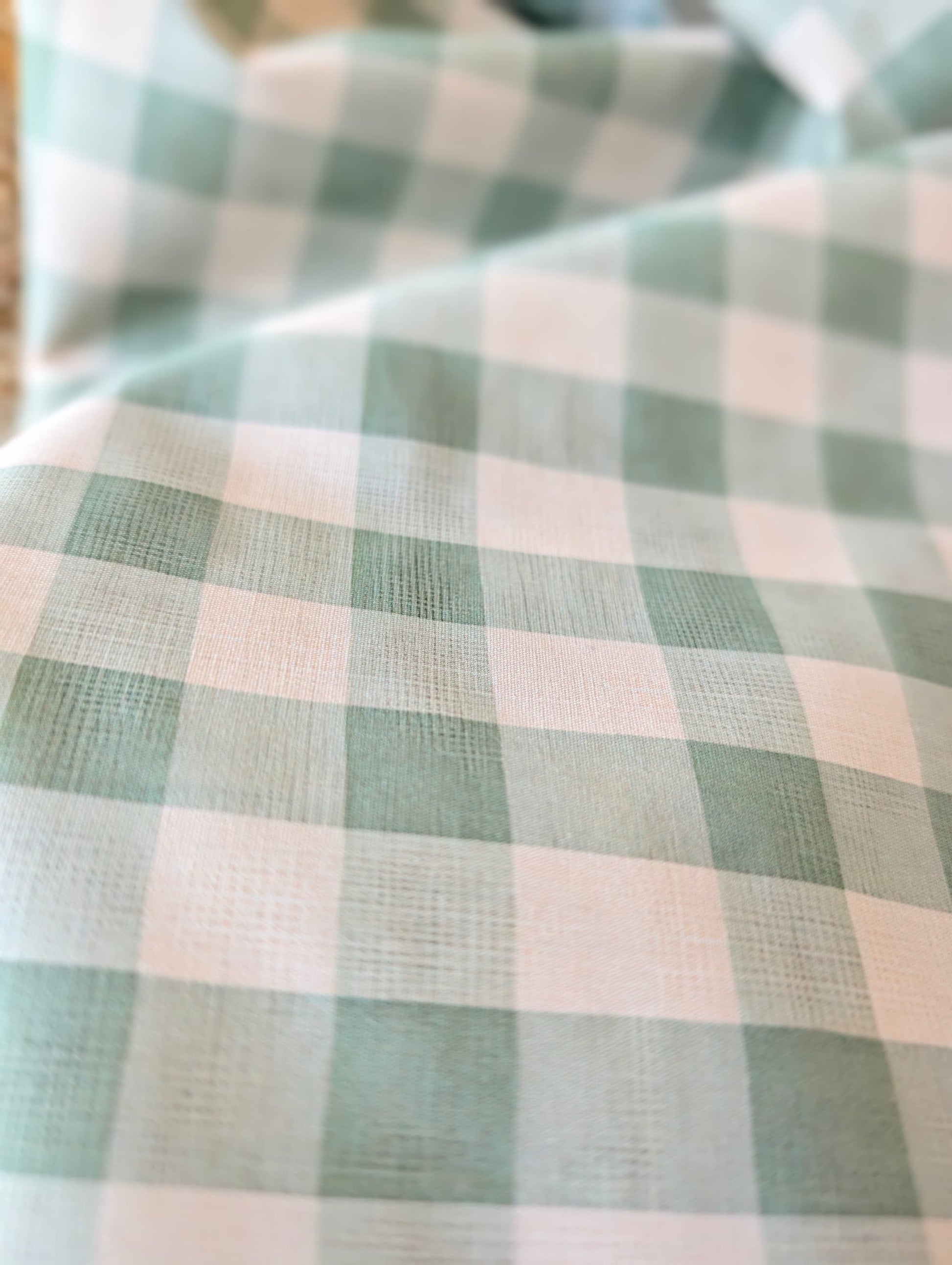 Celeste Sage Gingham Check Cotton — sage green and white gingham fabric draped over a wicker basket