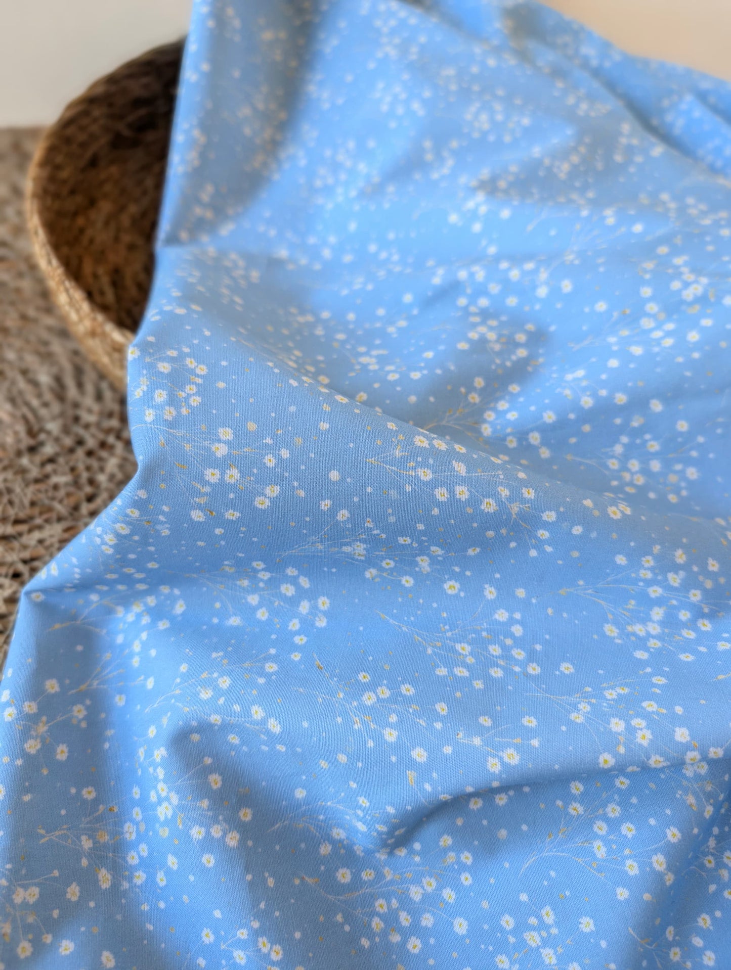 Clara Daisy Floral Cotton Poplin by esorai — scattered white daisy print on cornflower blue ground, fabric draped in wicker basket