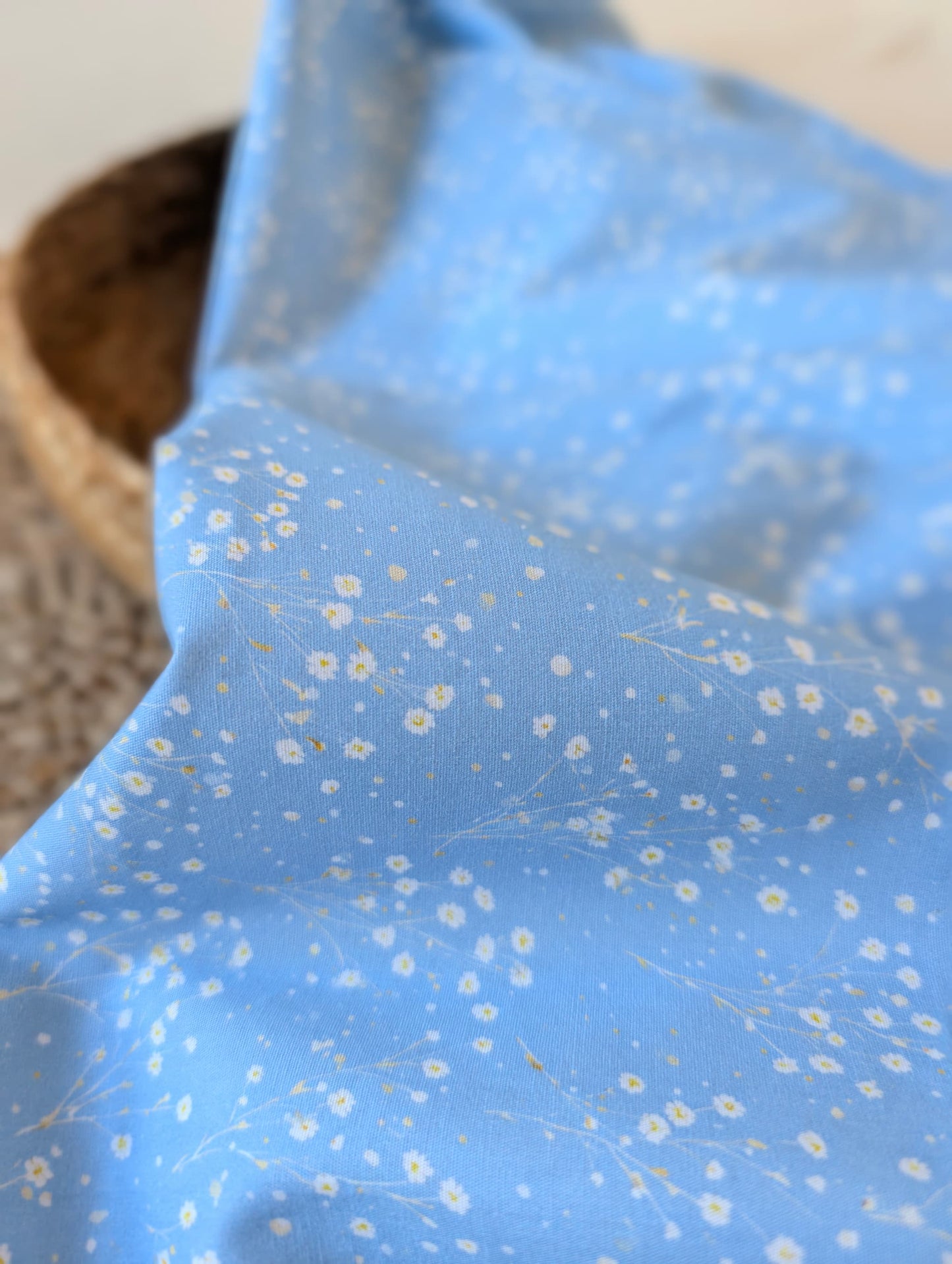 Clara Daisy Floral Cotton Poplin by esorai — scattered white daisy print on cornflower blue ground, fabric draped in wicker basket