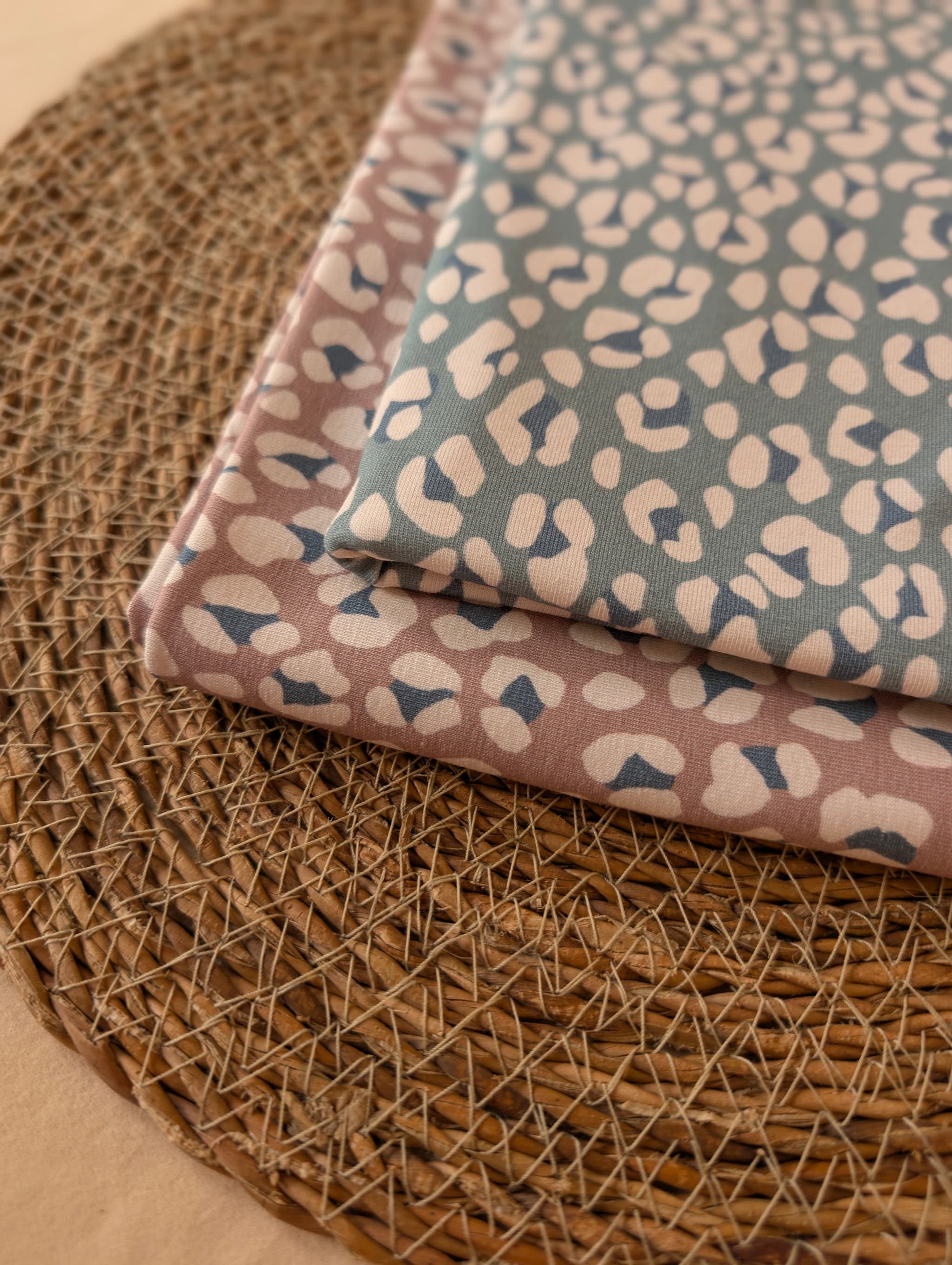 Cleo Leopard Cotton Jersey Duck Egg folded on wicker mat — angled view of exclusive leopard print in soft duck egg blue — Esorai