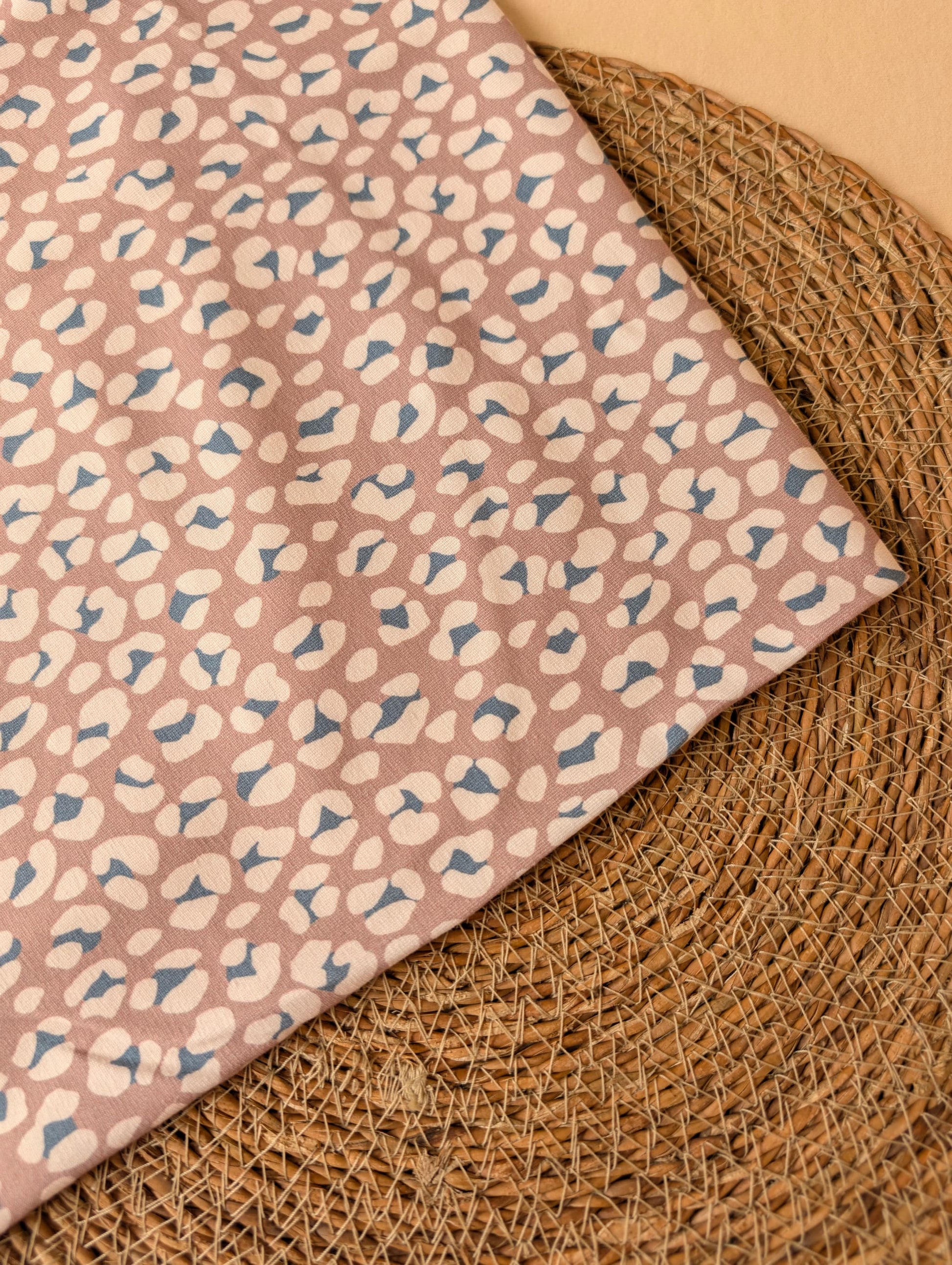 Cleo Leopard Cotton Jersey Mauve folded on wicker mat — angled view of exclusive leopard print in soft dusty mauve — Esorai