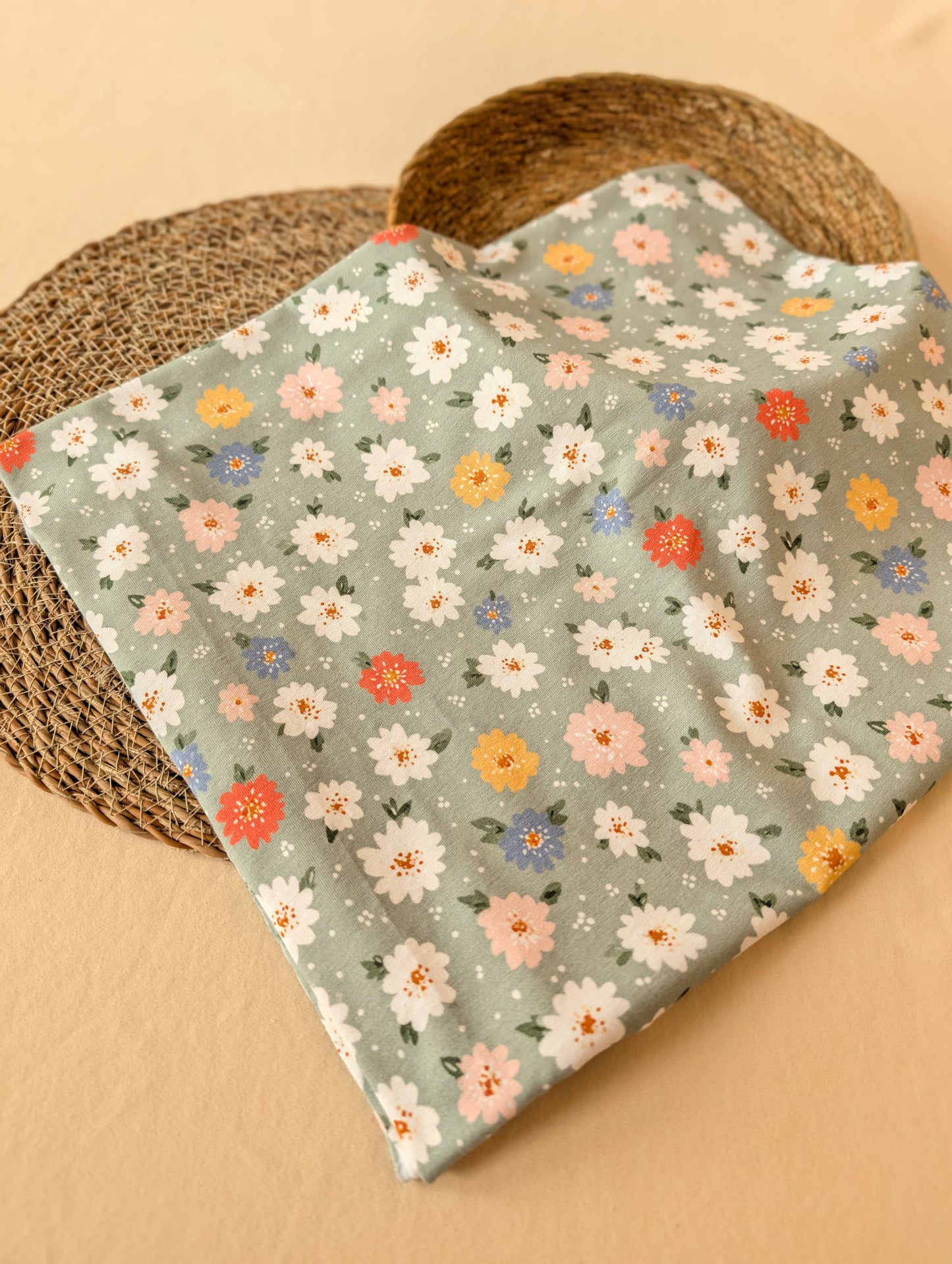 Daisy Floral Cotton Jersey in Sage folded flat on wicker mat — daisy print in warm neutral tones on muted sage green cotton jersey — Esorai