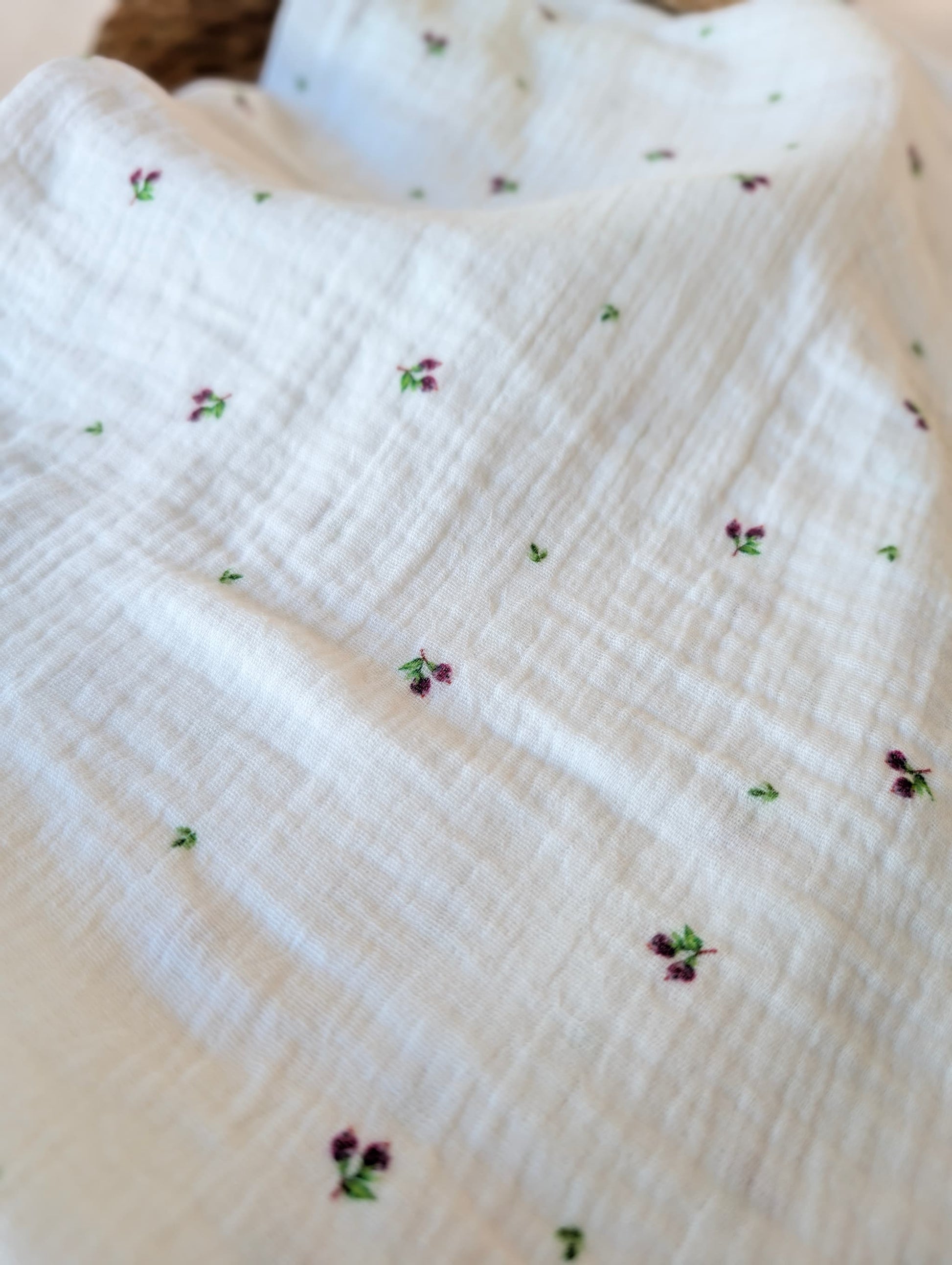Double gauze fabric draped loosely in a rattan basket showing soft drape — Mini Blueberries, tiny plum berry clusters and green leaves on white
