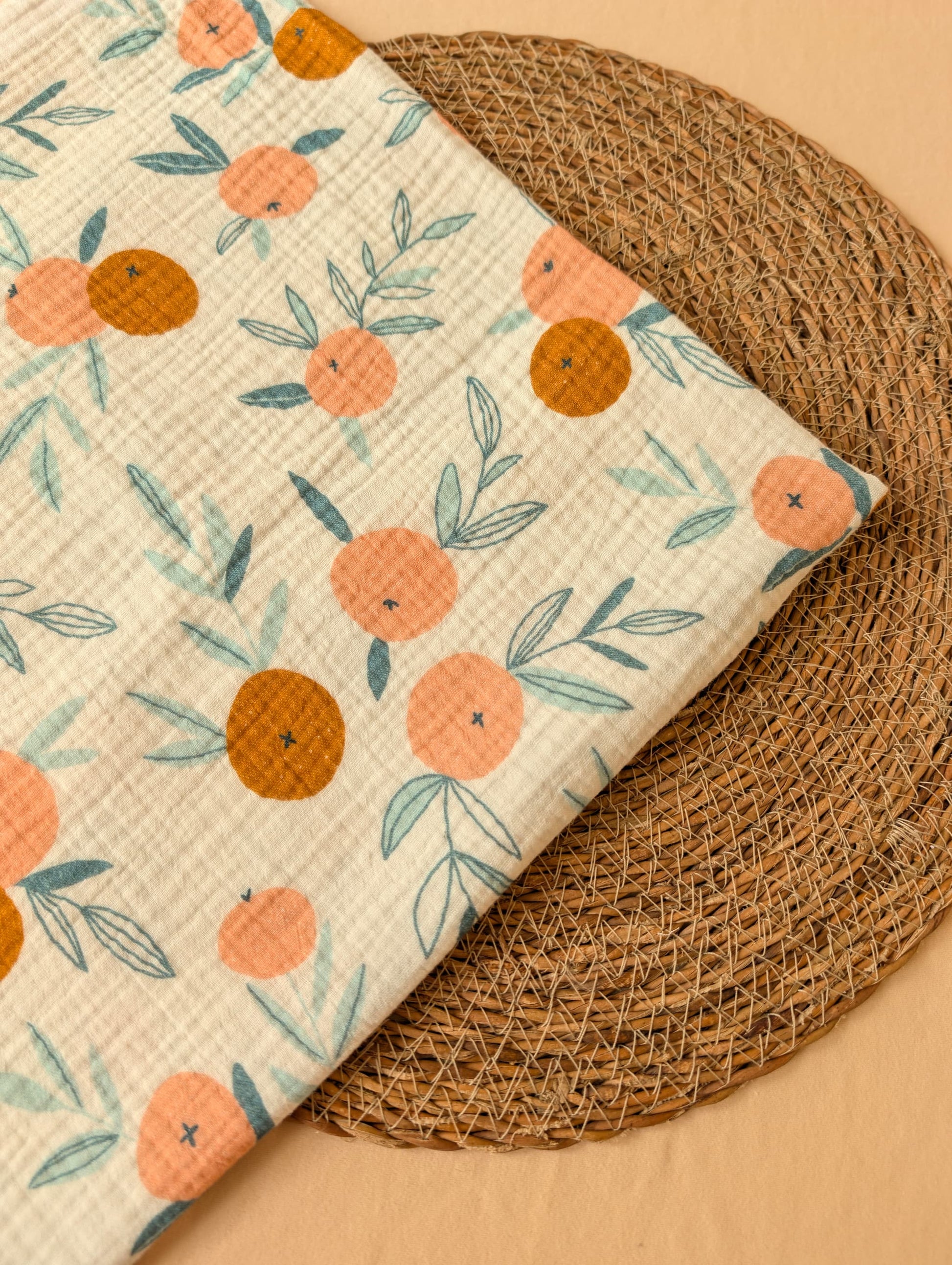 Fabric with orange and leaf pattern on a woven surface