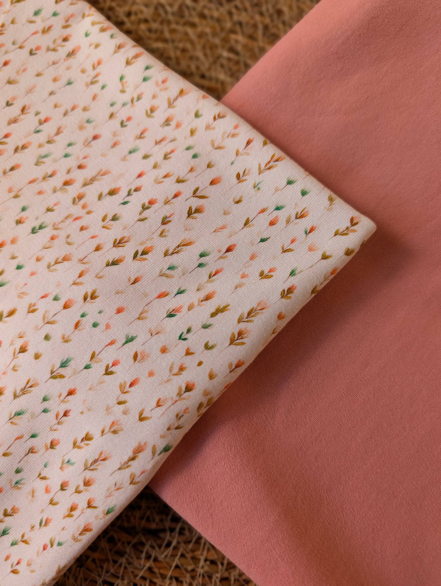 Cotton jersey Edie Sprig fabric folded alongside plain dusty pink cotton jersey — showing how the soft sprig print coordinates with a toning plain