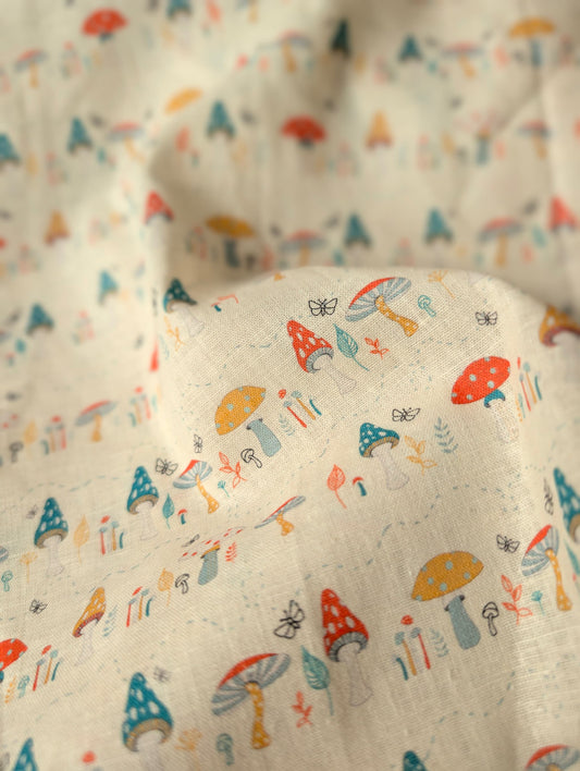 Close-up of linen cotton fabric draped and gathered — Hazel Woodland print showing individual toadstool varieties and botanical motifs in rich colour on natural
