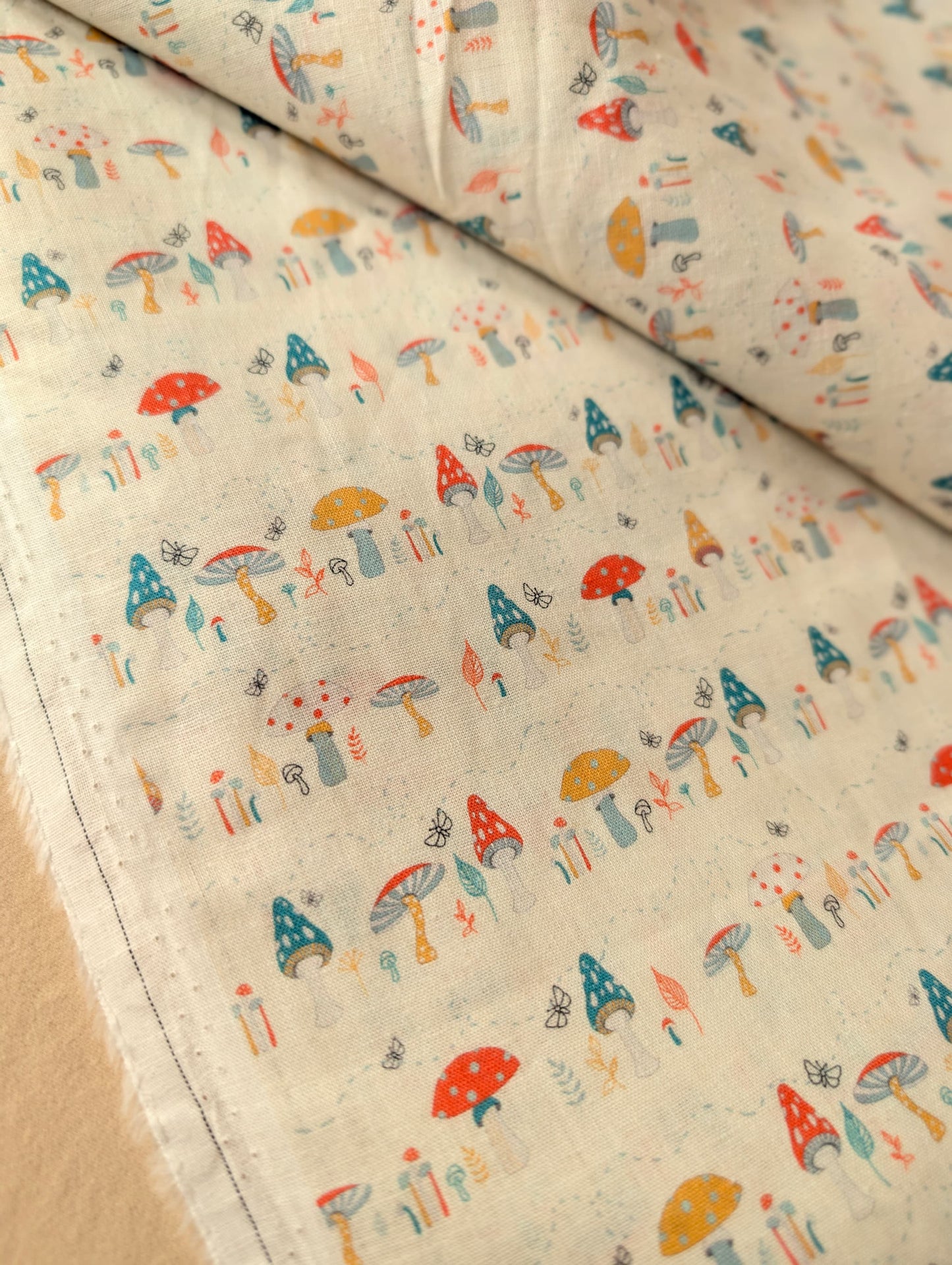 Premium linen cotton fabric showing drape and weave texture — Hazel Woodland exclusive print in red, teal and mustard on a natural base