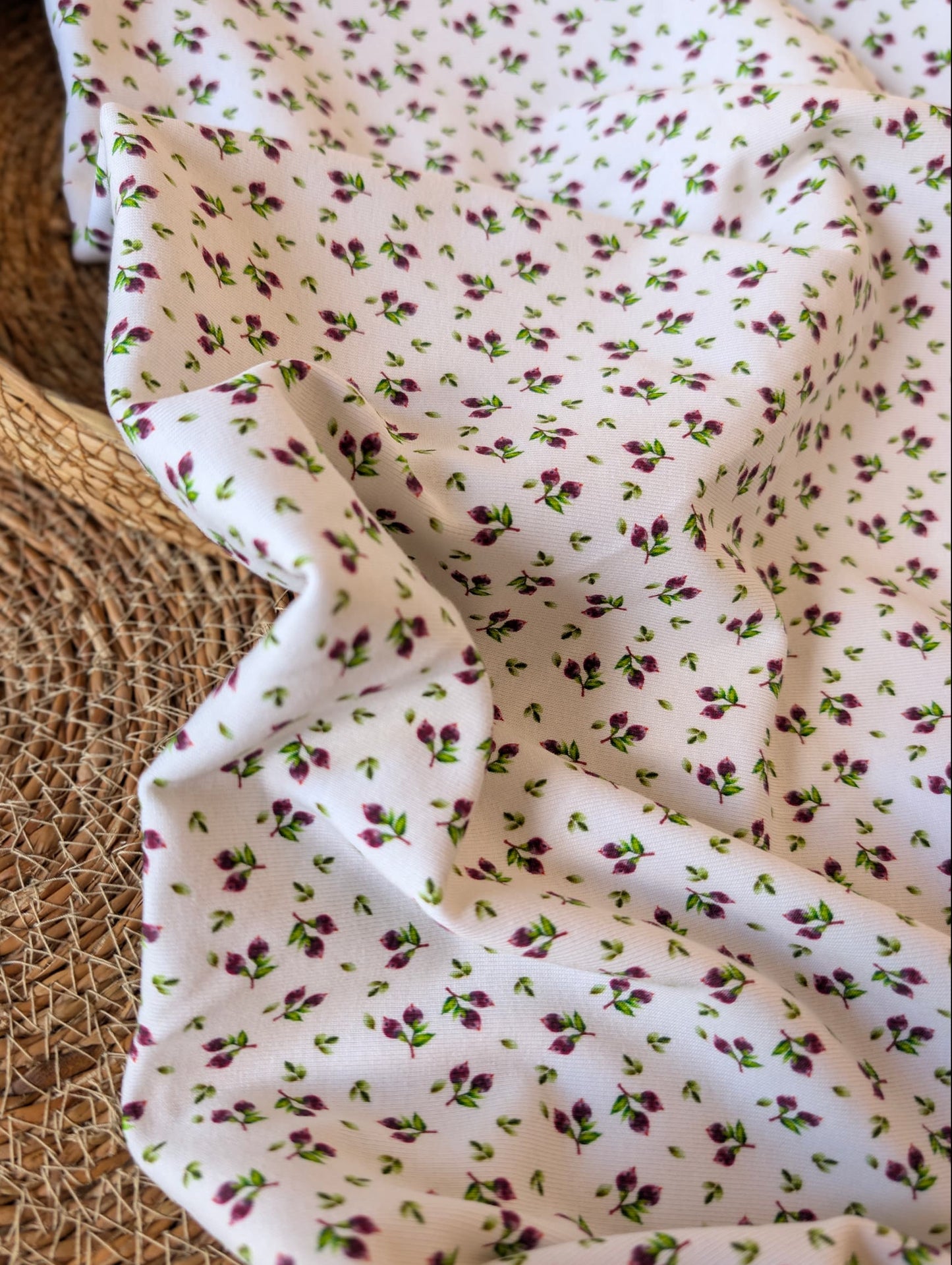 Cotton rib fabric draped in a rattan basket — Mini Blueberries, a ditsy print of plum berry clusters and green leaves on white