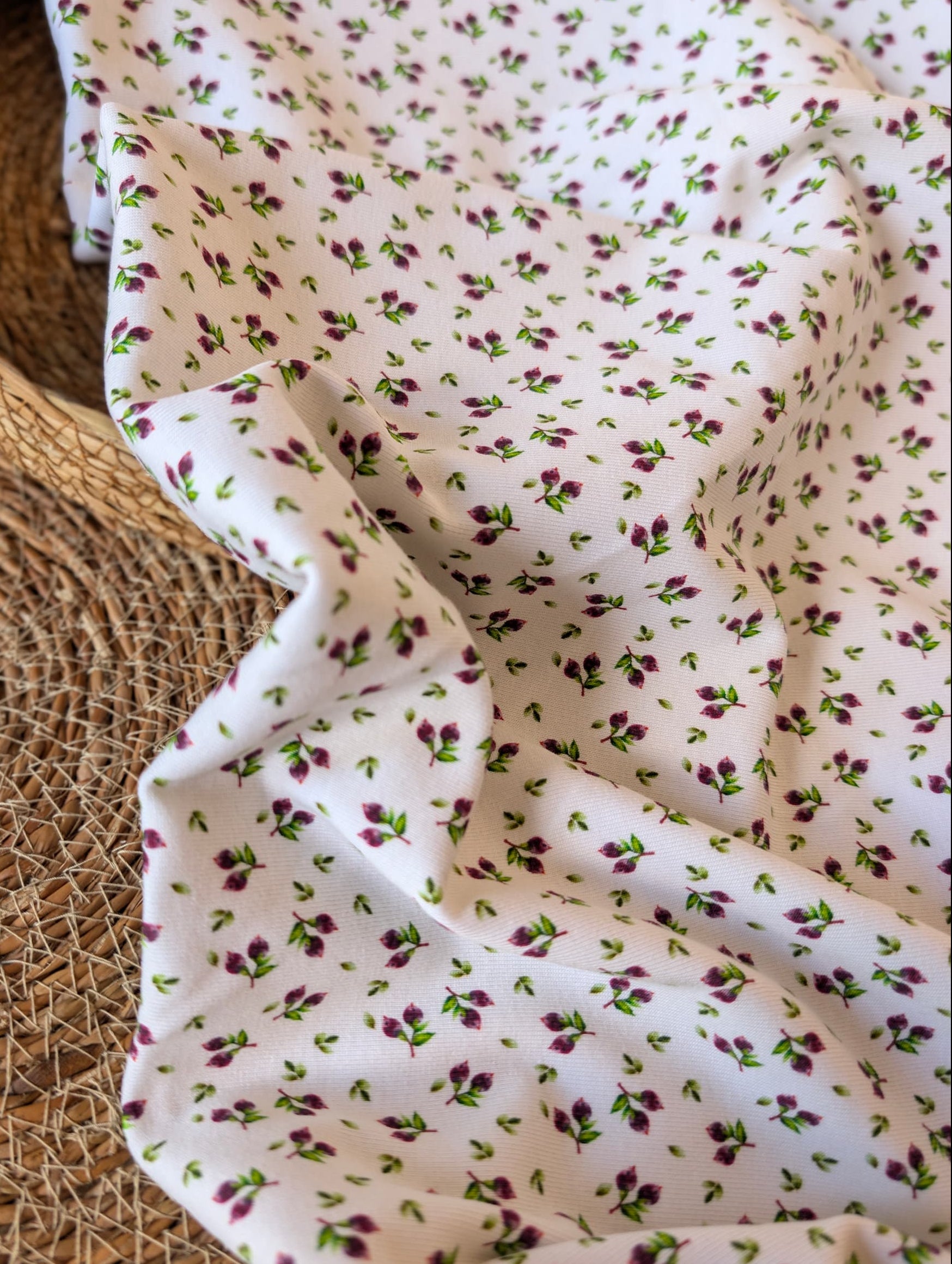 Cotton rib fabric draped in a rattan basket — Mini Blueberries, a ditsy print of plum berry clusters and green leaves on white