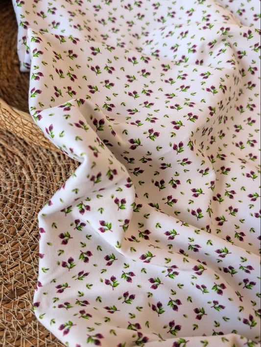 Cotton rib fabric draped in a rattan basket — Mini Blueberries, a ditsy print of plum berry clusters and green leaves on white
