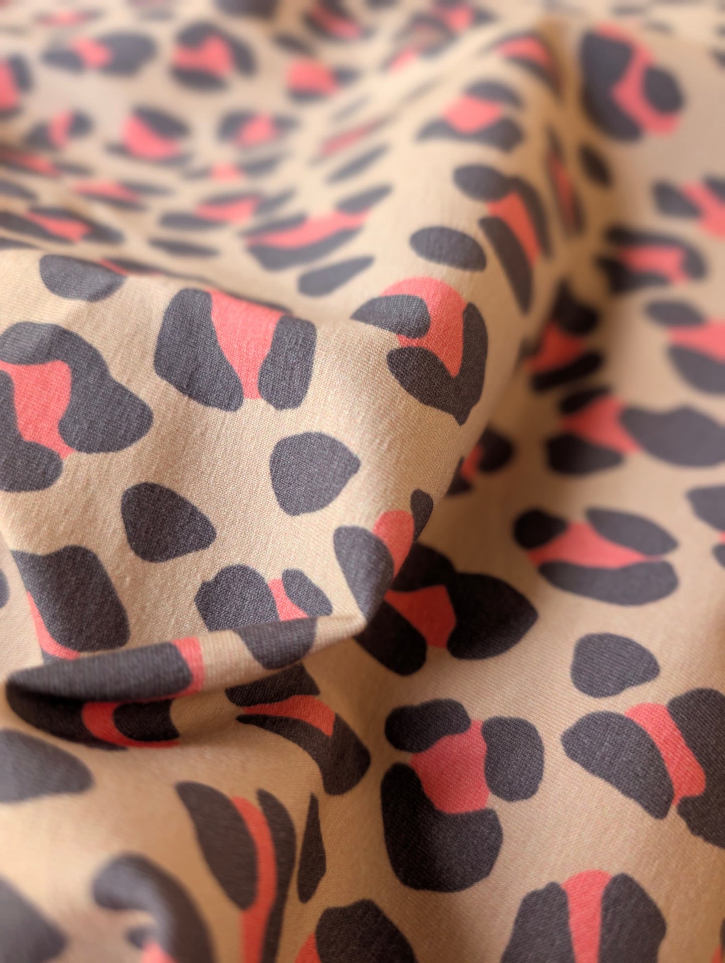 Close-up of Nala Animal Print cotton jersey showing print detail — large slate and coral leopard spots on a natural ground — Esorai