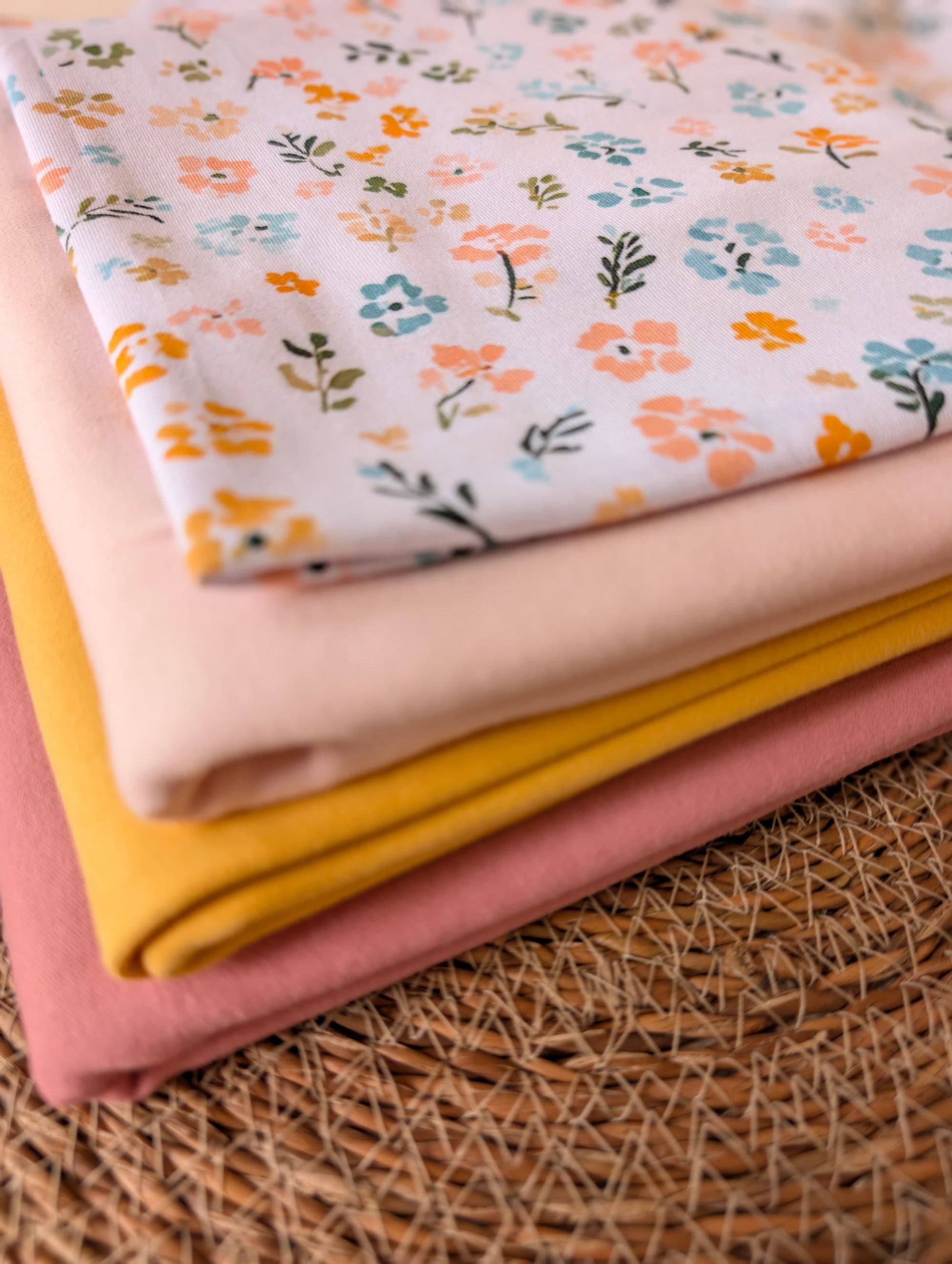 Cotton jersey Nell Floral fabric stacked with plain cotton jersey in blush, yellow and pink — pastel multi ditsy floral print on white