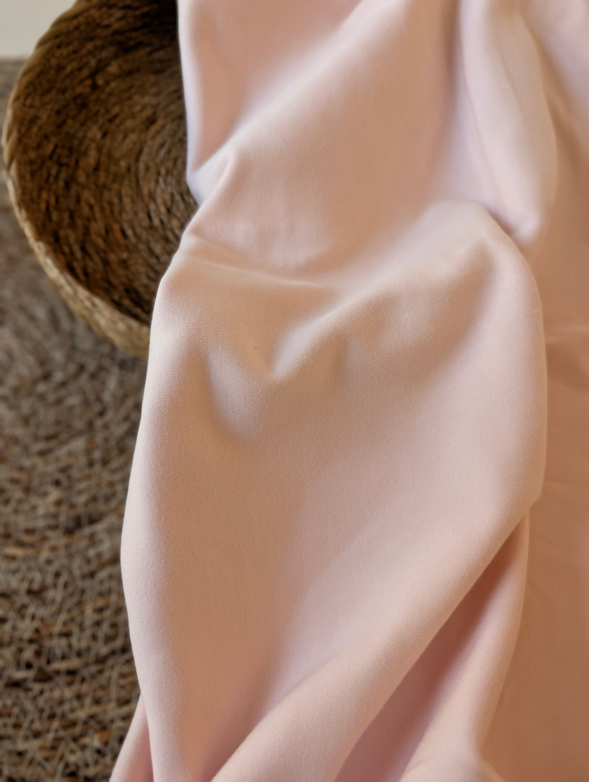 Pale blush pink premium-weight organic cotton jersey draped over a wicker basket — Cotton Jersey Plain in Blush by Esorai