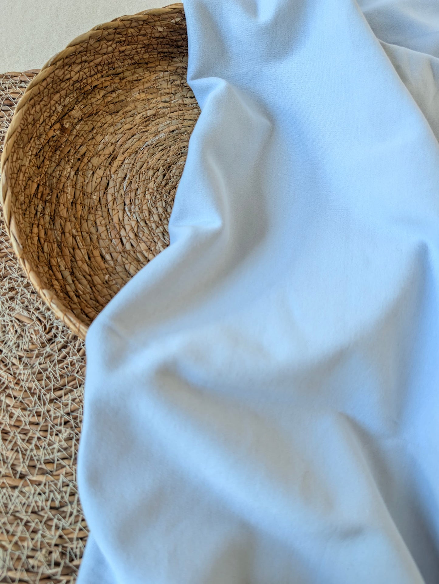 Pale powder blue premium-weight organic cotton jersey draped over a wicker basket — Cotton Jersey Plain in Powder by Esorai