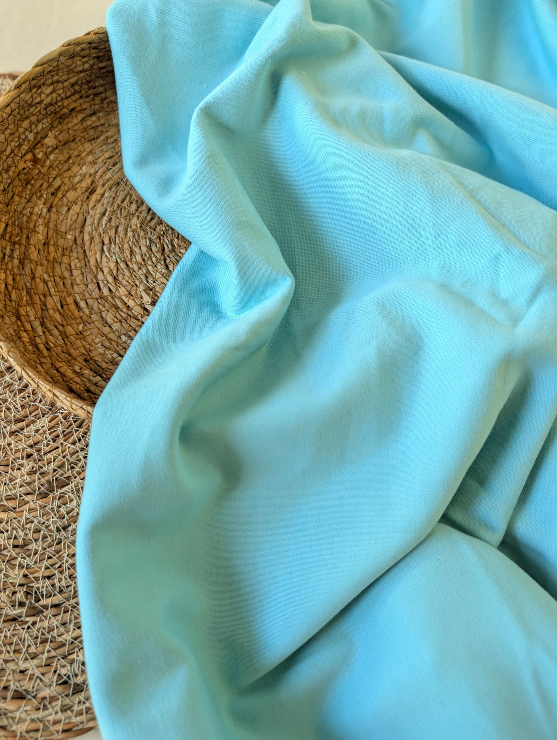 Aqua premium-weight organic cotton jersey draped over a wicker basket — Cotton Jersey Plain in Lagoon by Esorai