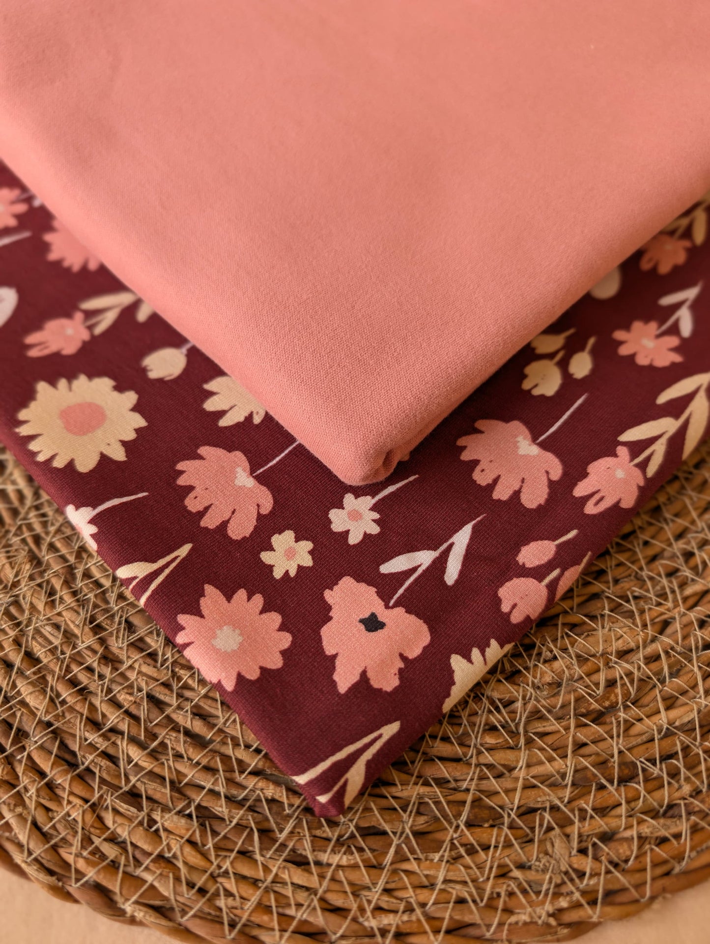 Ottie Floral Cotton Jersey in Burgundy stacked with Cotton Jersey Plain in Dusky Rose — styled together on a wicker mat by Esorai