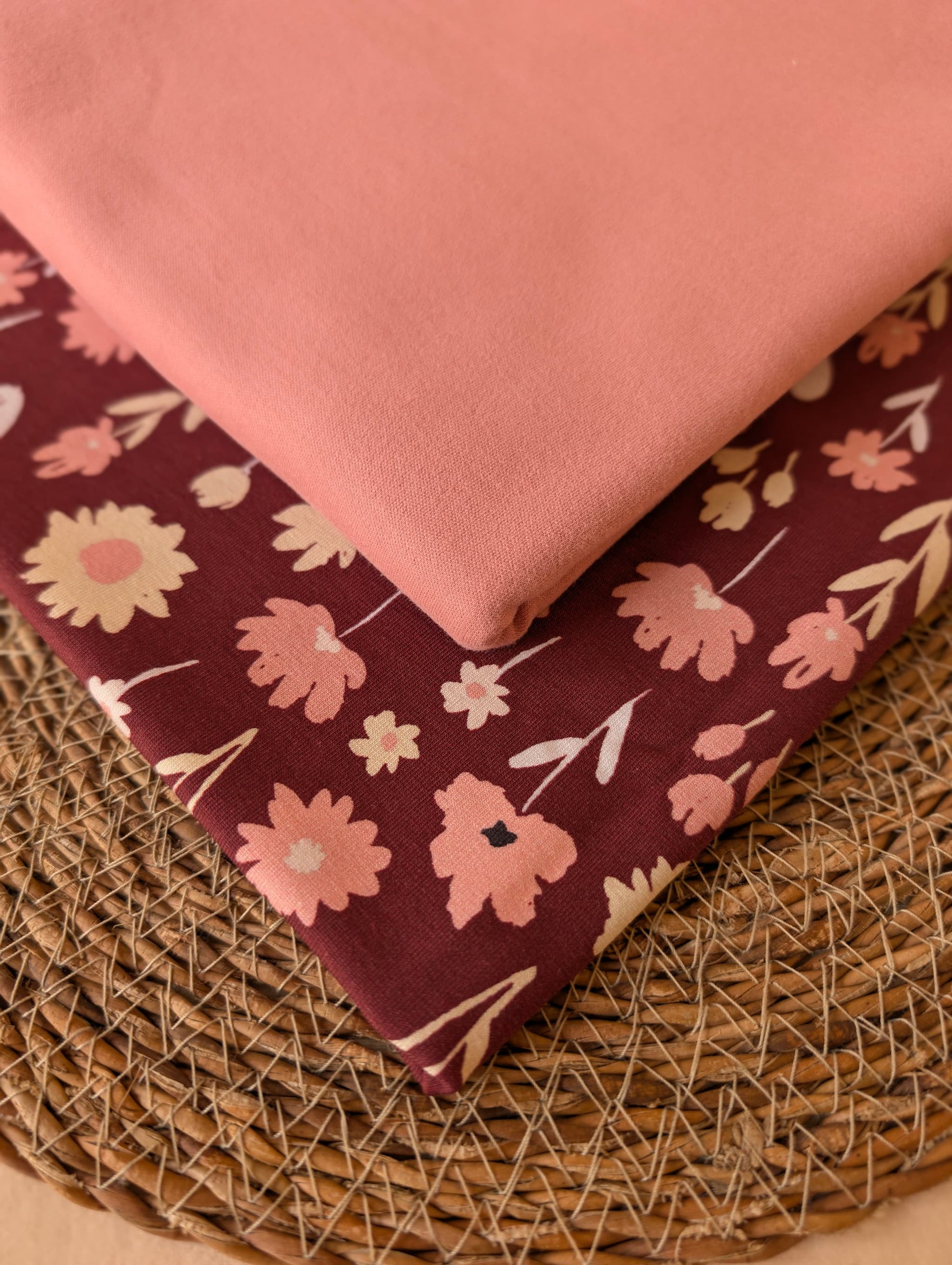 Ottie Floral Cotton Jersey in Burgundy stacked with Cotton Jersey Plain in Dusky Rose — styled together on a wicker mat by Esorai