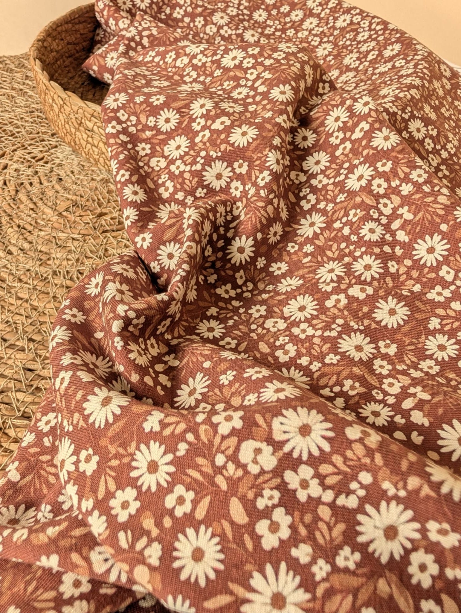 Willa Floral Cotton Jersey Rust — draped fabric showing soft stretch and all-over ditsy daisy print with cream flowers and tan leaves on chocolate brown ground