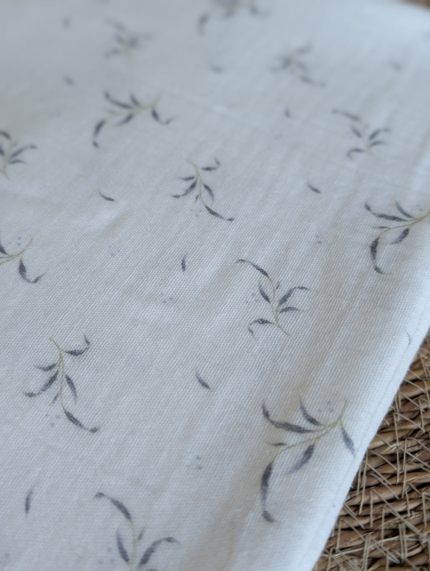 Winnie double gauze fabric draped flat showing the full scattered leaf sprig print layout on lilac-white ground