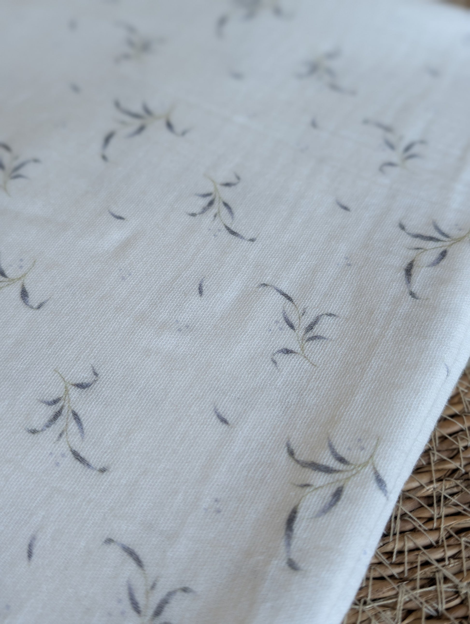 Winnie double gauze fabric draped flat showing the full scattered leaf sprig print layout on lilac-white ground