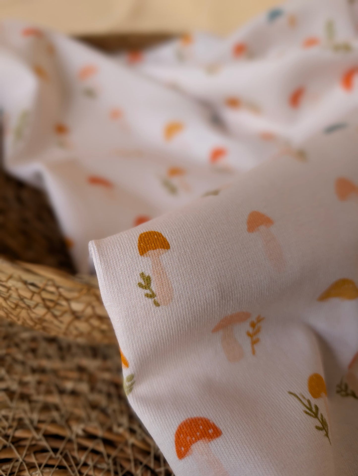 Close-up of white cotton rib fabric showing individual toadstool motifs and botanical sprigs — Wren toadstool print in autumnal tones